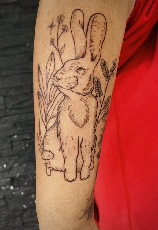 Tatuaje Conejo Botánico en Brazo — versión Blanco y Negro (Trazo Fino) por Alma Lila Tattoo Studio